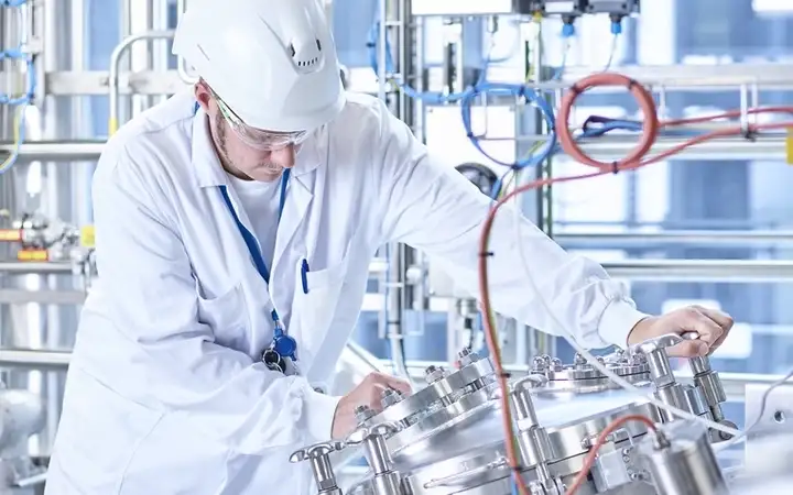 Man in white overalls and hat working in an industrial plant