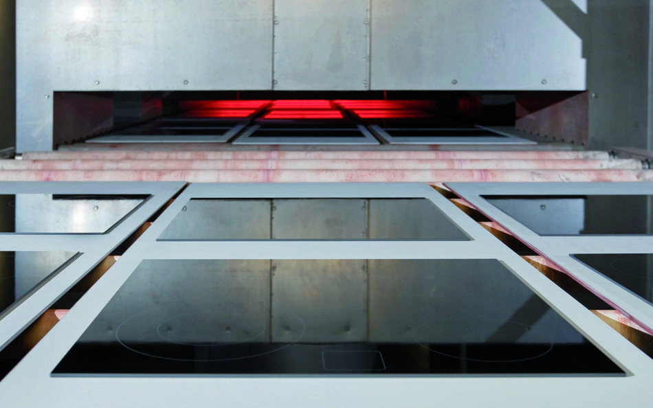 	Panels of black SCHOTT CERAN® glass-ceramic cooktop panels entering an industrial oven 