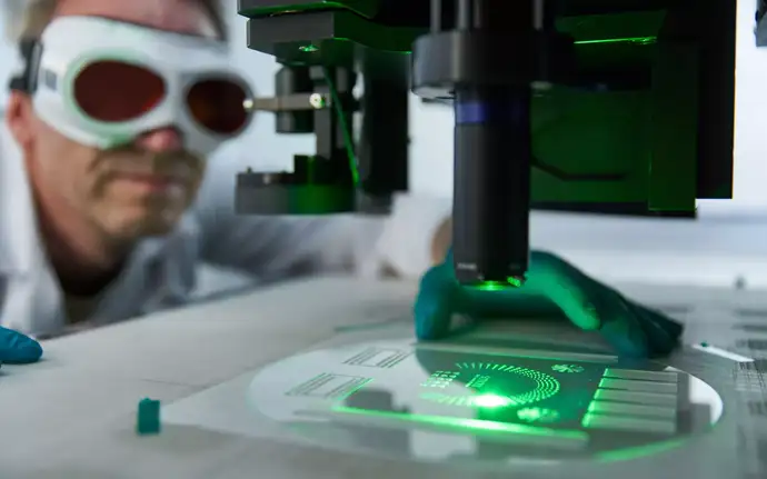 Wissenschaftler bei der Betrachtung einer laserstrukturierten Glasscheibe	