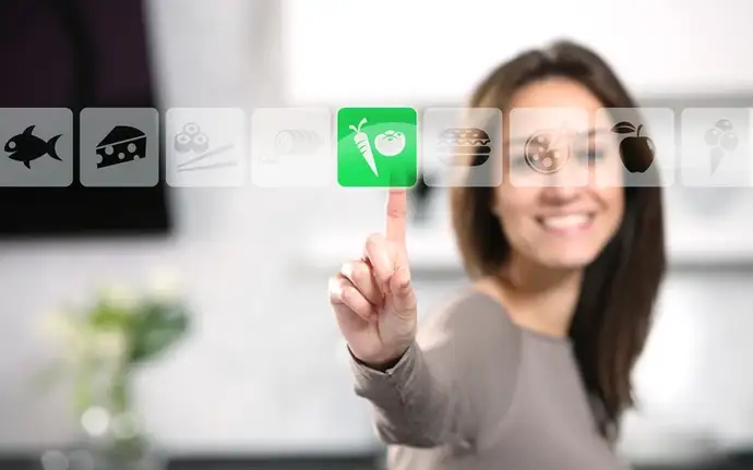 Mujer sonriente haciendo el gesto de pulsar un botón verde de una pantalla táctil 