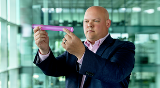 A man holding a pink laser glass rod.
