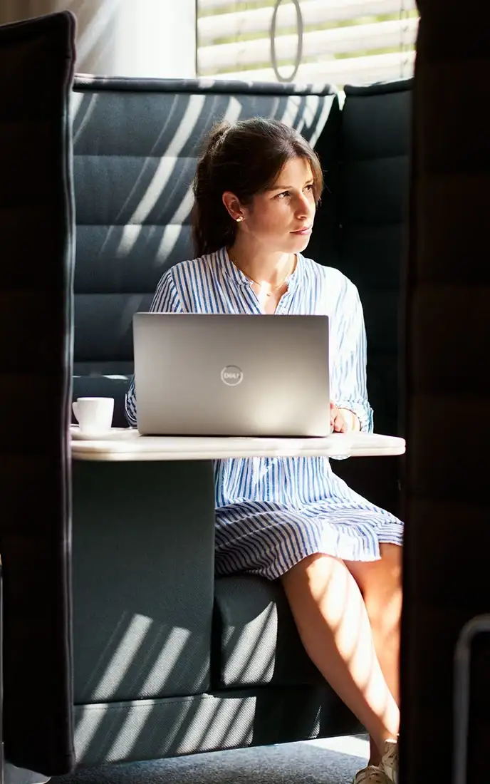 A woman works on a laptop in a seating area