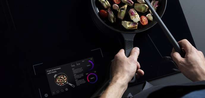 Person rührt Gemüsepfanne auf CERAN® Kochfläche mit Touchscreen-Bedienung 