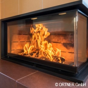 Roaring fire in indoor fireplace with SCHOTT ROBAX® angular bent fire-viewing panel
