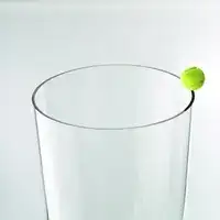 Yellow tennis ball balanced on the rim of a clear glass tube