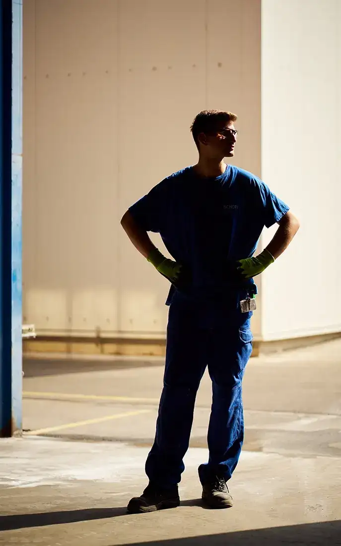 Imagem de corpo inteiro de um trabalhador de produção da SCHOTT em roupa de trabalho azul