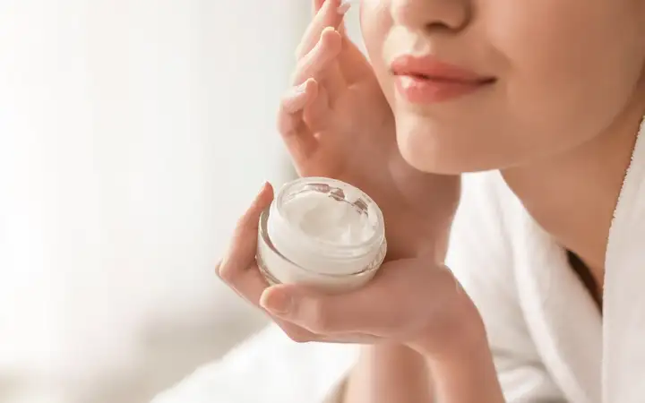 Female applying face cream to her cheek