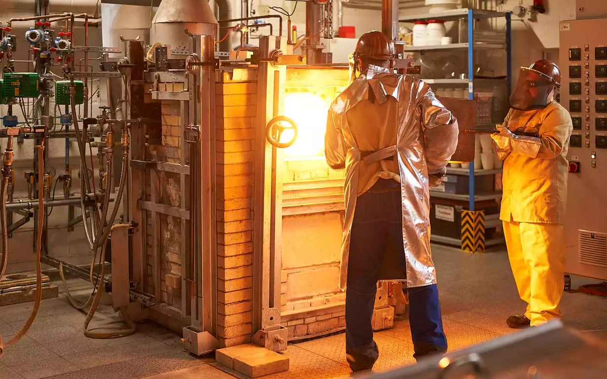 Two men in heat protection suits in front of the test furnace