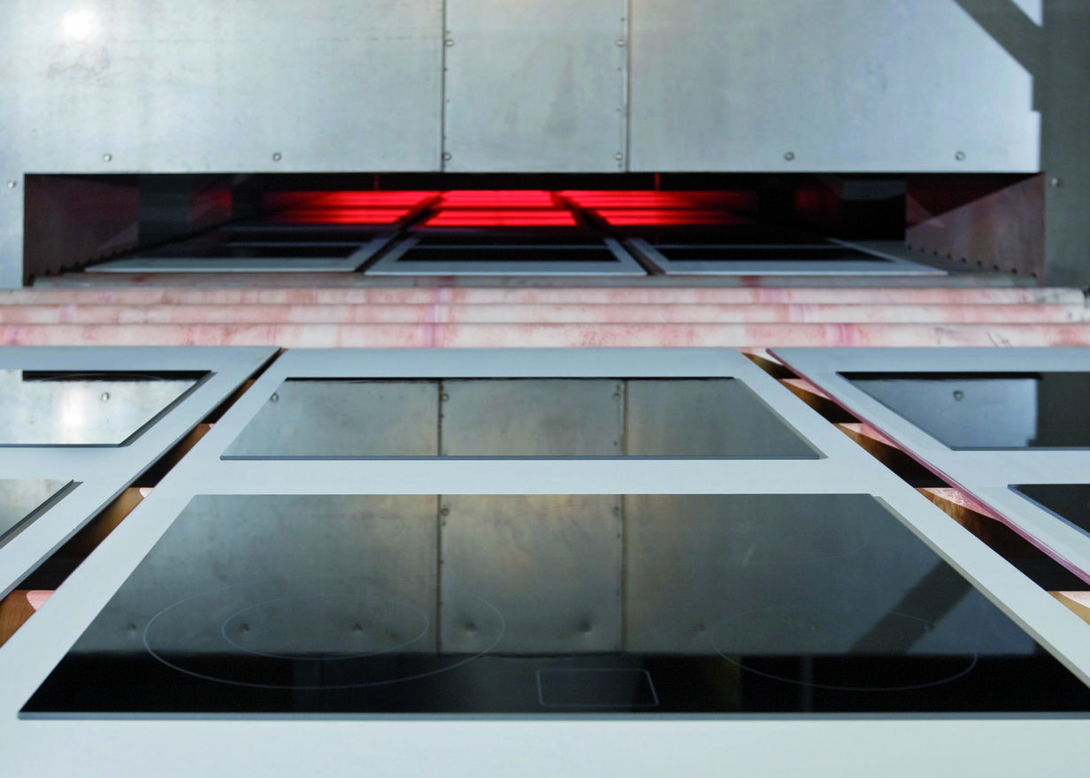 Panels of black SCHOTT CERAN® glass-ceramic cooktop panels entering an industrial oven 