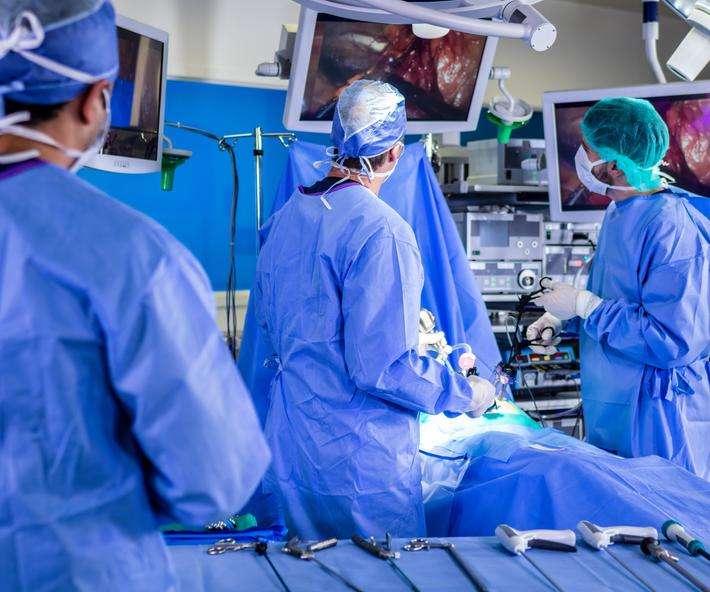 Doctors watch HD monitors while performing minimally invasive robotic surgery