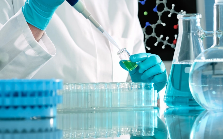 Scientist in a laboratory filling a series of clear glass vials