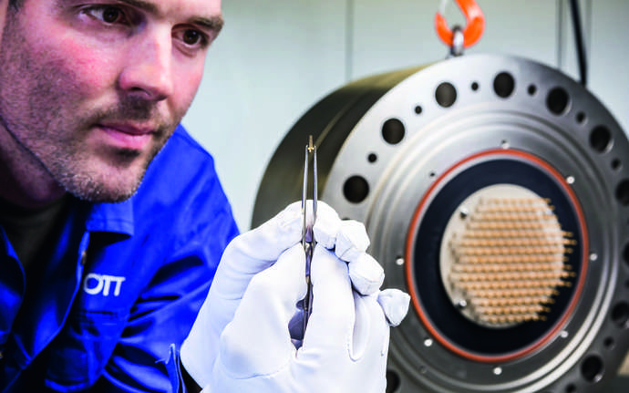 Man holding tiny component with tweezers.