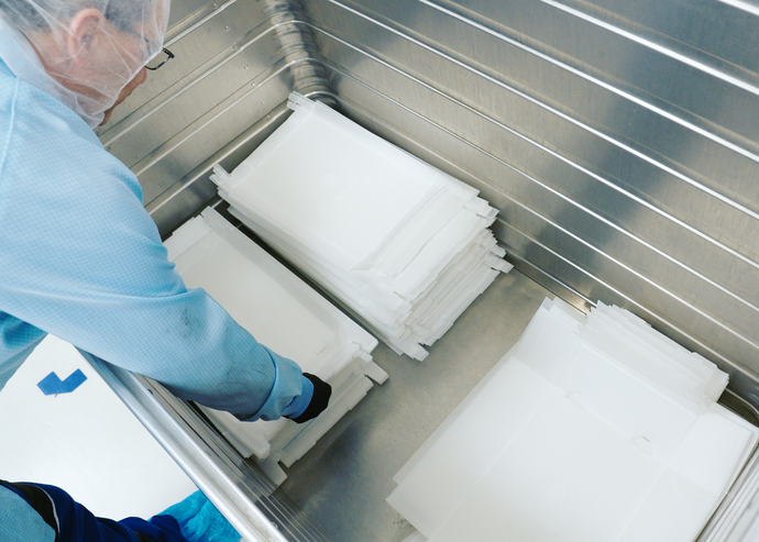 Person putting flattened and stacked pharma trays in box for closed-loop recycling.