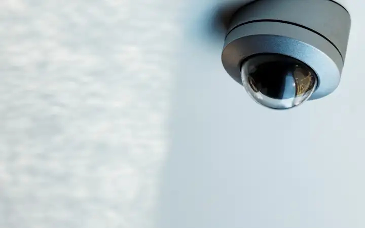 Small grey ceiling-mounted security camera