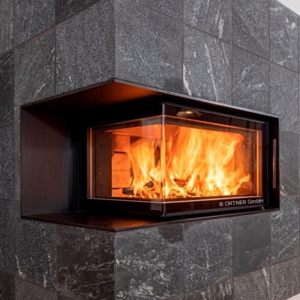 Close up of an indoor fireplace with SCHOTT ROBAX® angular bent fire-viewing panel surrounded by gray stone