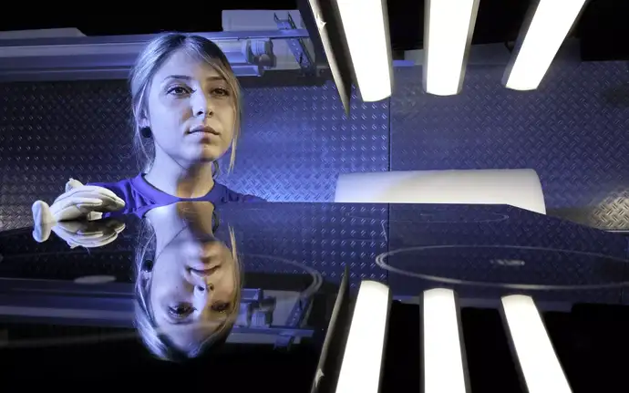 Young woman checking the quality of a CERAN cooktop in the production process.