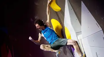 Man punches the air while climbing a boulder wall