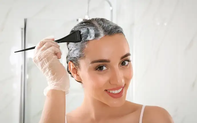 Femme appliquant une teinture capillaire avec un pinceau.