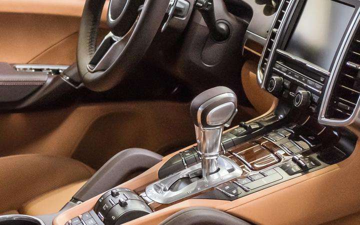 Brown interior of a luxury vehicle with dashboard, steering column and gear stick