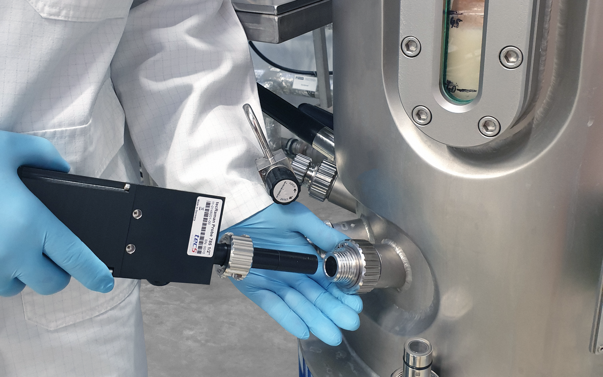 Close-up of a scientist examining a bioreactor while using a Raman spectrometer with a SCHOTT ViewPort® interface