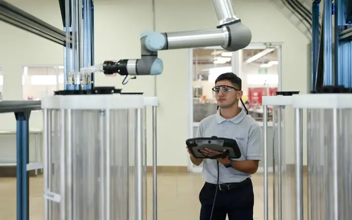 Production worker with a tablet besides a robot