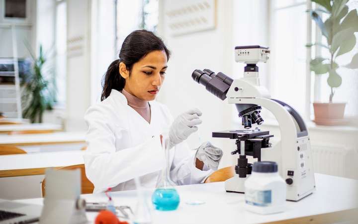 Scientist using microscope in pharmaceutical lab for research