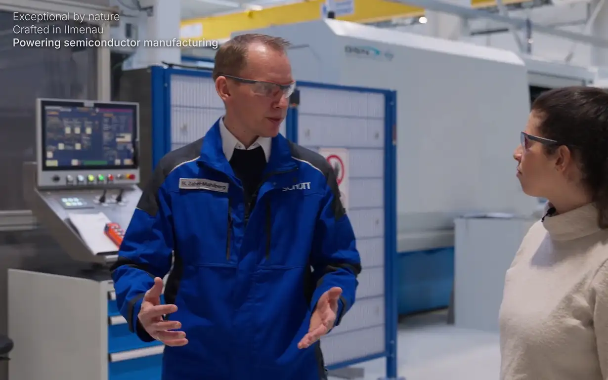 Two individuals in a manufacturing setting wearing safety goggles, discussing near advanced equipment with text overlay about semiconductor production.
