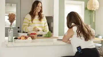 A woman wearing an iLet Bionic Pancreas on her hip eats lunch with a friend.