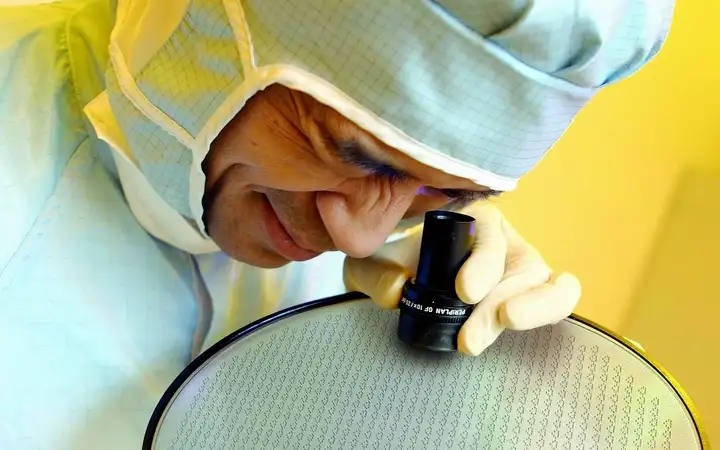 Scientist inspecting a large glass wafer