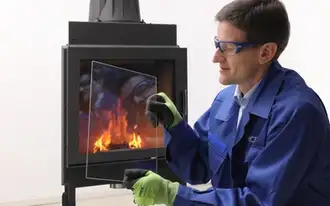 SCHOTT ROBAX® application engineer holding a ROBAX® IR Max panel with heat-reflective coating in front of a fireplace