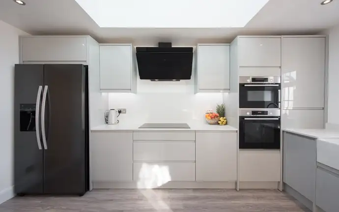 Modern kitchen interior with glass looking like stainless steel and a black extractor hood made of glass.
