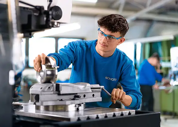 Eine Person bedient eine industrielle Maschine und positioniert präzise ein Metallteil.