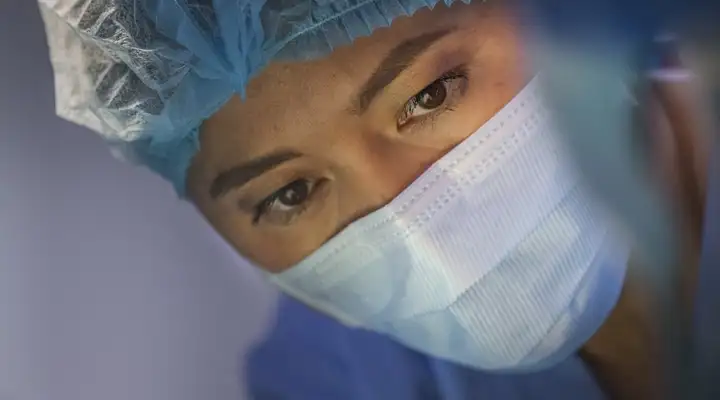 Female surgeon looking at a patient in a hospital operating theatre