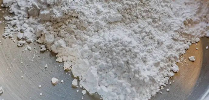 White glass powder in a metal dish