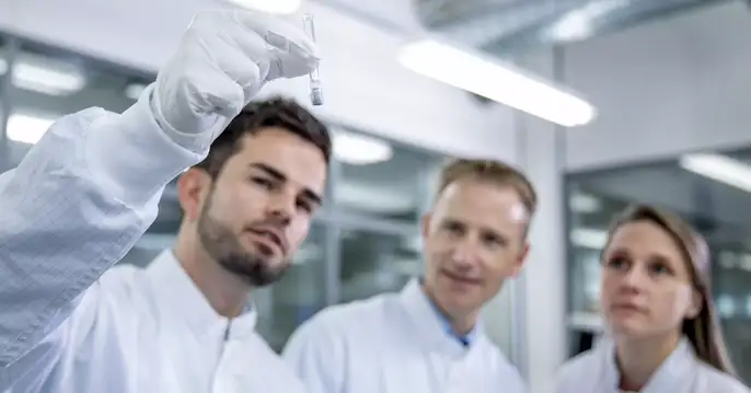 Groupe de laborantins regardant une seringue pour le contrôle visuel