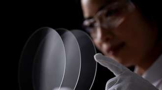 An Asian researcher looks through a glass carrier wafer