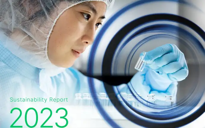 Woman in cleanroom clothing holding a pharmaceutical vial for quality control.