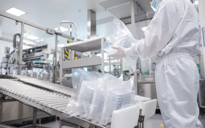 SCHOTT TOPPAC® nest-and-tub packaging for prefillable polymer syringes being handled in a pharmaceutical cleanroom manufacturing environment.