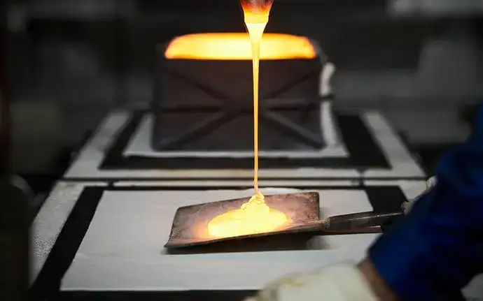 Molten, glowing glass flowing onto a ladle for further processing