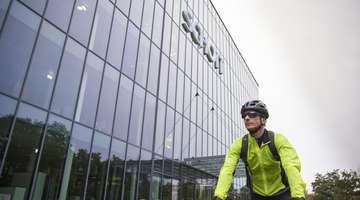 Michael Hahn arrives at SCHOTT in Mainz by bike, wearing a bright green jacket