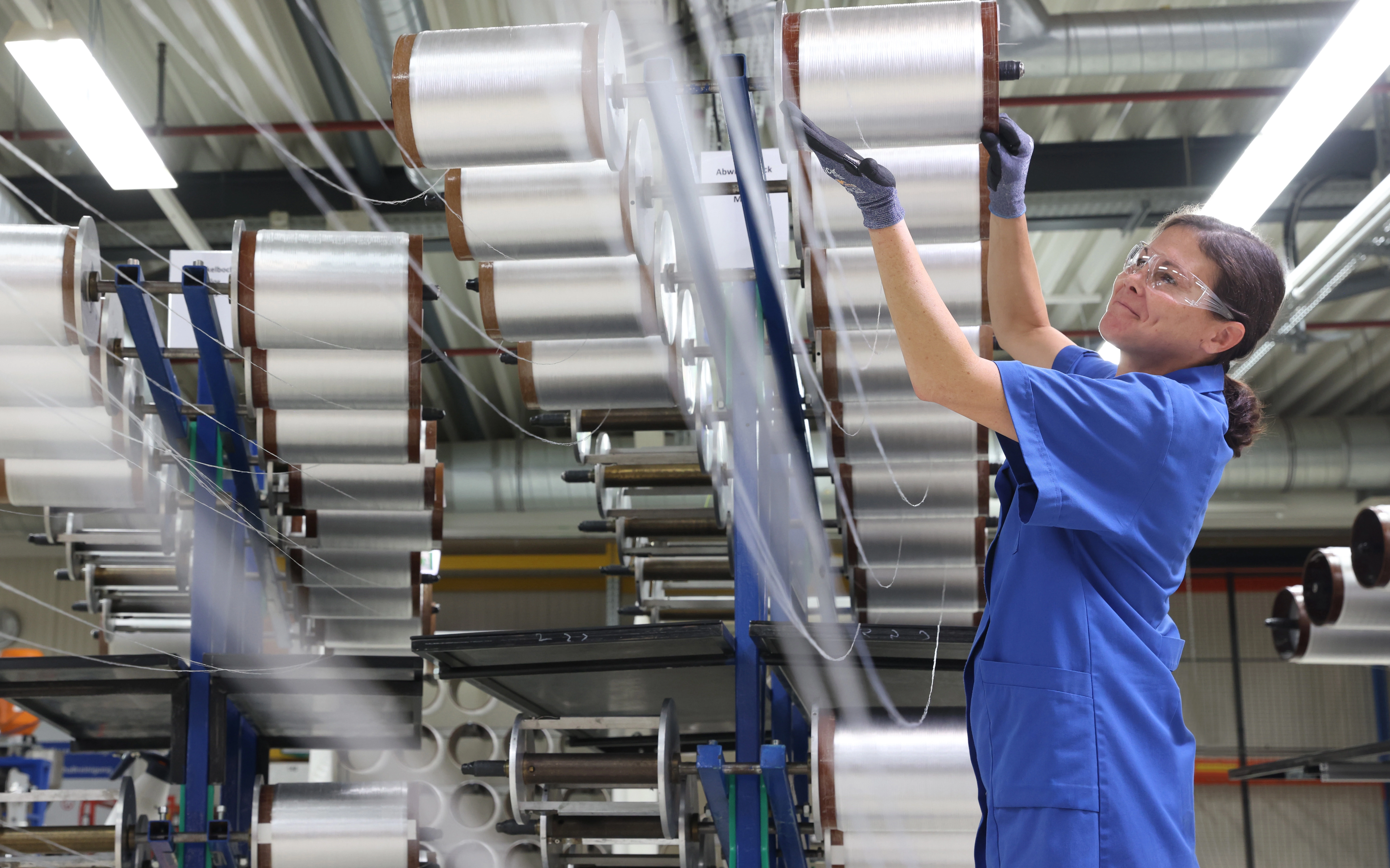 一名工作人员在产线上检视用于医疗和工业领域的玻璃光纤